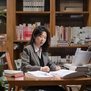 内容总监林晓雅坐在工作台前专注审阅稿件，桌面整洁，旁边摆放着日本相关书籍，呈现出细致严谨的内容把关态度
